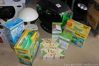 Photo showing black Aero Garden hydroponic unit, Grass Shot seeding kits, Aqua Clear box, plastic dome cover, seed kits, and other garden items.