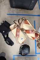 Two beige canvas and leather Fogg camera bags with adjustable straps and two small black camera bags on floor.