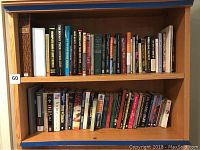 Wide view of wooden shelves filled with assorted books, showing the overall quantity and arrangement.