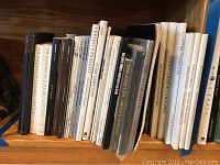Image showing an assortment of photography and art books lined side-by-side on a wooden shelf. Titles include Edward Weston volumes, Sotheby's auction catalogs, and other photography books.