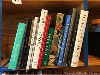 Shelf photo showing 12 artist and photography books in a row, various titles and colors, some focus on New Mexico photography and Mapplethorpe.