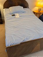 Full bed showing headboard, footboard, mattress and remote on top