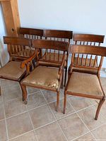 Front view of six wooden dining chairs with upholstered seats