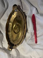 Top view of gold-glazed oval tray alongside red pen for scale