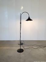 Full view of black arched cone floor lamp illuminated