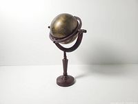 Full view of brass globe on wood pedestal