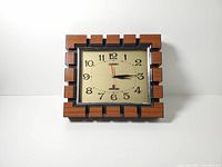 Front view of wall clock showing faux wood frame and dial