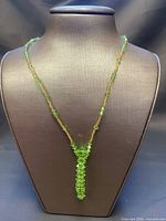 Full view of green beaded necklace on bust showing overall design and pendant length