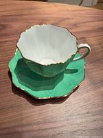 Teacup on saucer showing color, gold trim, shape