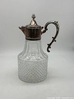 Full view of claret jug showing glass body and silver-plated top and handle