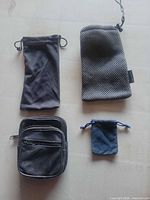 Four pouches laid out: black microfiber, gray mesh, black faux leather zip pouch, dark blue microfiber
