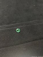Round green faceted stone on black background