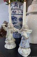 Both porcelain angel candle holders with tapers inserted, showing overall appearance