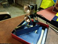 Vintage automatic movie light kit on table, showing dual reflective bulb heads attached to metal bracket, inside original box.