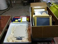 Box containing over 20 picture frames, some wood framed with glass, and a decorative mirror.