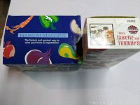 Two boxed kitchen items placed side by side showing the Blossom Machine and the Rosette and Timbale set.