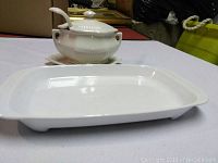White Adams gravy boat with lid and underplate placed behind a white Corning rectangular baking tray.