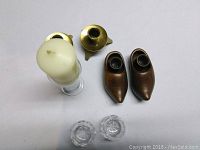 Photo of seven candle holders including brass, glass, wooden shoe-shaped, and cut glass types.