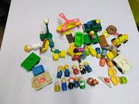 Overview showing multiple Little People figures, vehicles, and play accessories scattered on white surface.