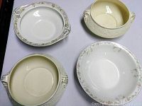 Top view of four ceramic serving bowls on white background, showing different patterns and handles.