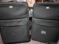Two large black Ricardo suitcases side by side, showing front view with zippered compartments and handles.