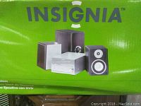 Box front showing Insignia logo and image of stereo system including main unit, subwoofer, and two speakers.