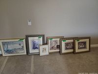 Six framed artworks lined up against wall showing relative sizes and frames