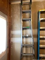 Full view of aluminum extension ladder leaning against wall