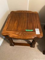Full view of carved wood side table showing top, legs and stretcher
