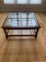 Full view of square coffee table showing glass panels and wood frame