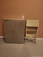 Table folded upright beside folded step stool