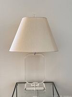 Front view of Lucite lamp unlit on glass table