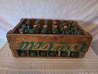 Front view of wooden Coca-Cola crate filled with green bottles