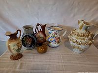 Group shot of all six ceramic pitchers and vase
