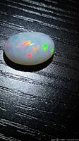 Oval Ethiopian opal showing multicolour flashes on dark background