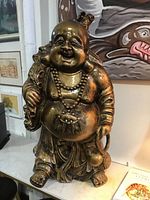 Front view of large bronze-tone laughing Buddha statue on console table