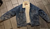 Front view of entire jacket laid flat showing denim exterior and sherpa lining