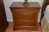 Front view of one nightstand showing two lower drawers and brass handles.
