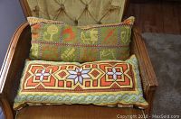 Close-up photo showing two decorative needlepoint pillows on the chair seat.