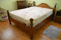 Full view of assembled bed frame with mattress on pine flooring