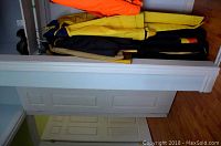 Multiple men's rain and snow suits hanging on a rod, including yellow and dark colors, showing items in lot