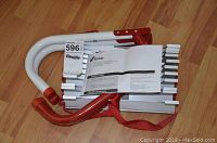 Folded Kidde emergency escape ladder with aluminum rungs and red hooks resting on wooden floor. Manual placed on top.