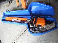 Open case showing orange Stihl chainsaw with 16" bar and cover, plus parts bag
