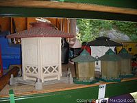 Wide view showing all four birdfeeders on shelf, including the large beige hexagonal feeder and three smaller feeders with green roofs, two hanging by chains.