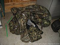 Folded camouflage pop-up tent or blind with carry bag on floor in storage area