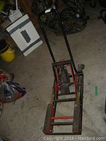 Full view of the hydraulic ATV jack showing red and black frame and pump handle.