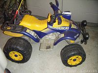 Side view of the child's Peg Perego battery powered ATV showing yellow seat, blue body, and large wheels.