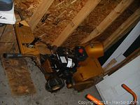 Side view of Viking gas-powered snow blower showing yellow paint, engine, and tires inside a wooden shed.