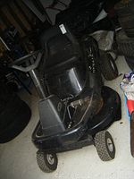 Side/front angle of black Murray Select mower showing deck, wheels and seat area
