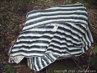 Cement mixer covered with a striped fabric cover outdoors.